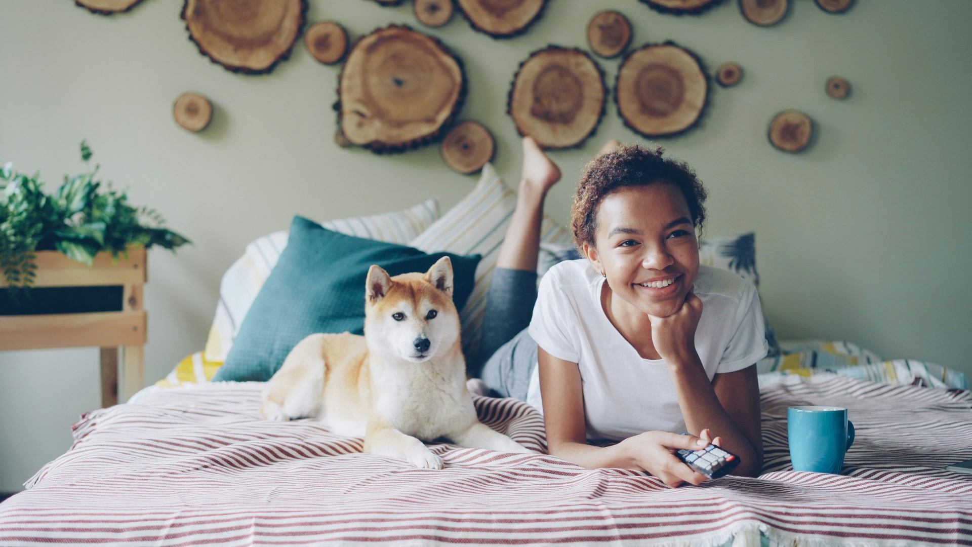 Young woman relaxing on bed with her Shiba Inu dog in a pet-friendly apartment